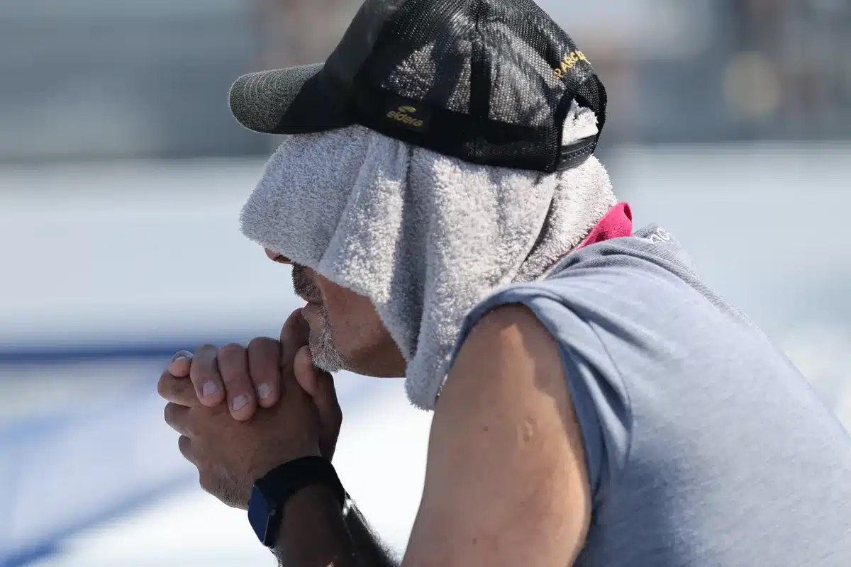 How to progress in petanque: training, technique and the mental game 2 Focused petanque player with a towel over his head and his hands clasped in front of his mouth, during a game