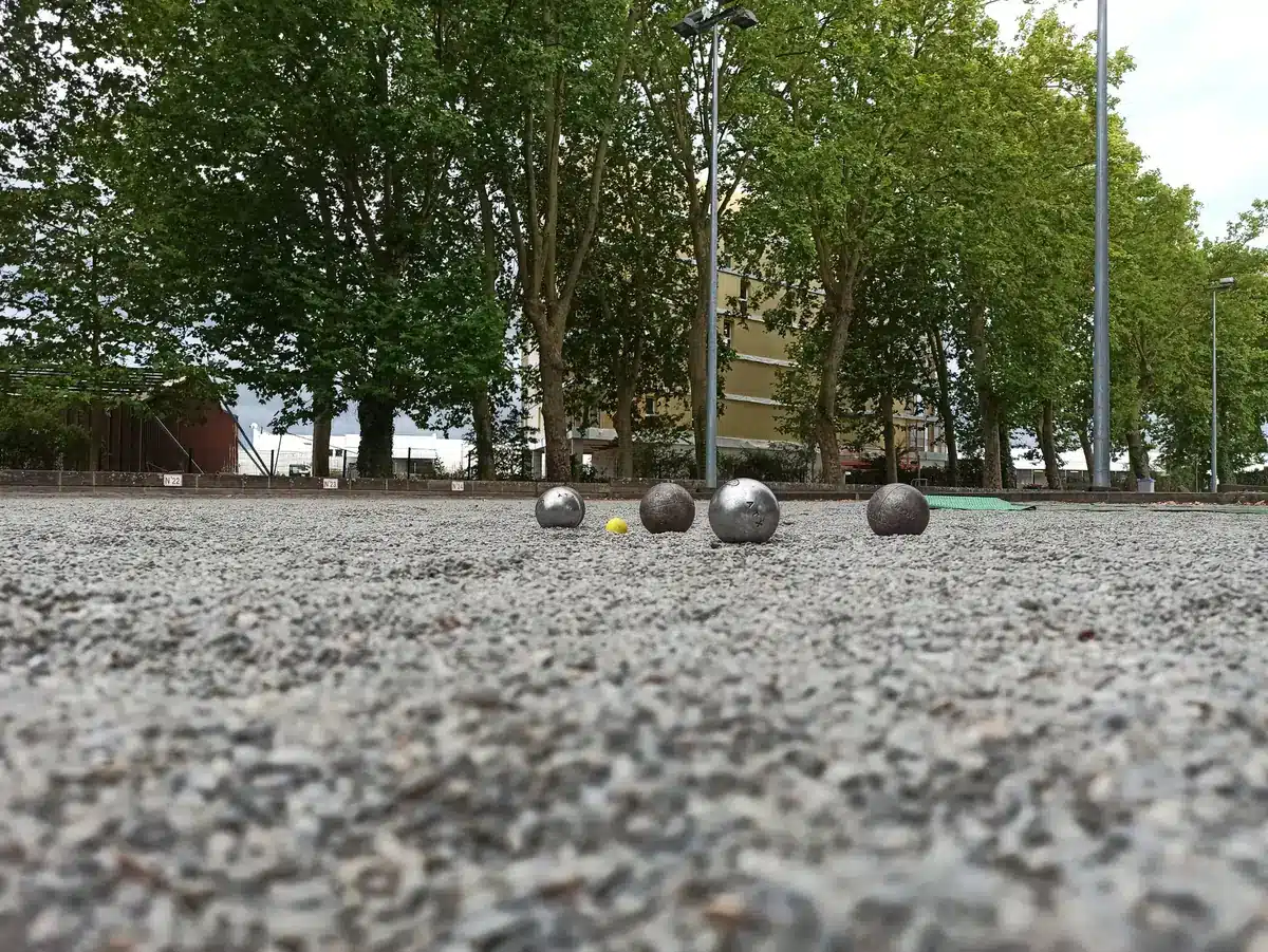 Pourquoi marquer le cochonnet à la Pétanque ? La règle et les bons gestes 2 Terrain de Pétanque en gravier vu au ras du sol, avec le cochonnet et les boules au loin